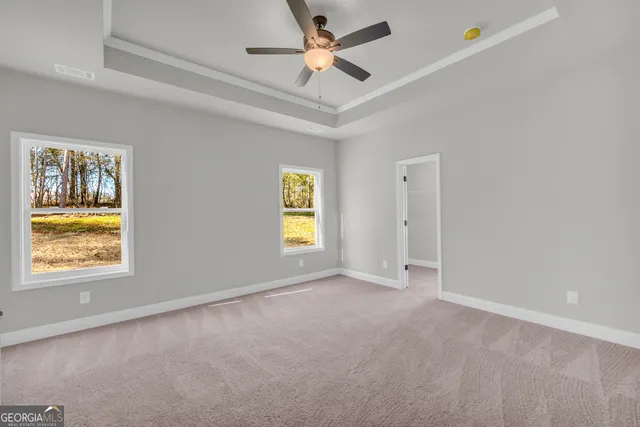 a view of an empty room with a window and a kitchen