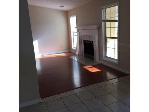 a view of an empty room with window and wooden floor