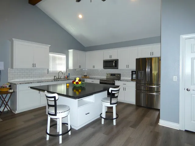 a kitchen with a refrigerator a stove top oven a sink dishwasher and white cabinets with wooden floor
