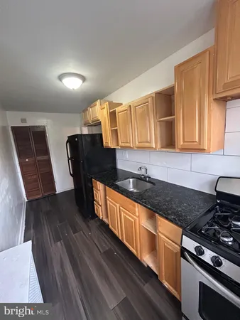 a kitchen with granite countertop wooden cabinets a stove and a sink