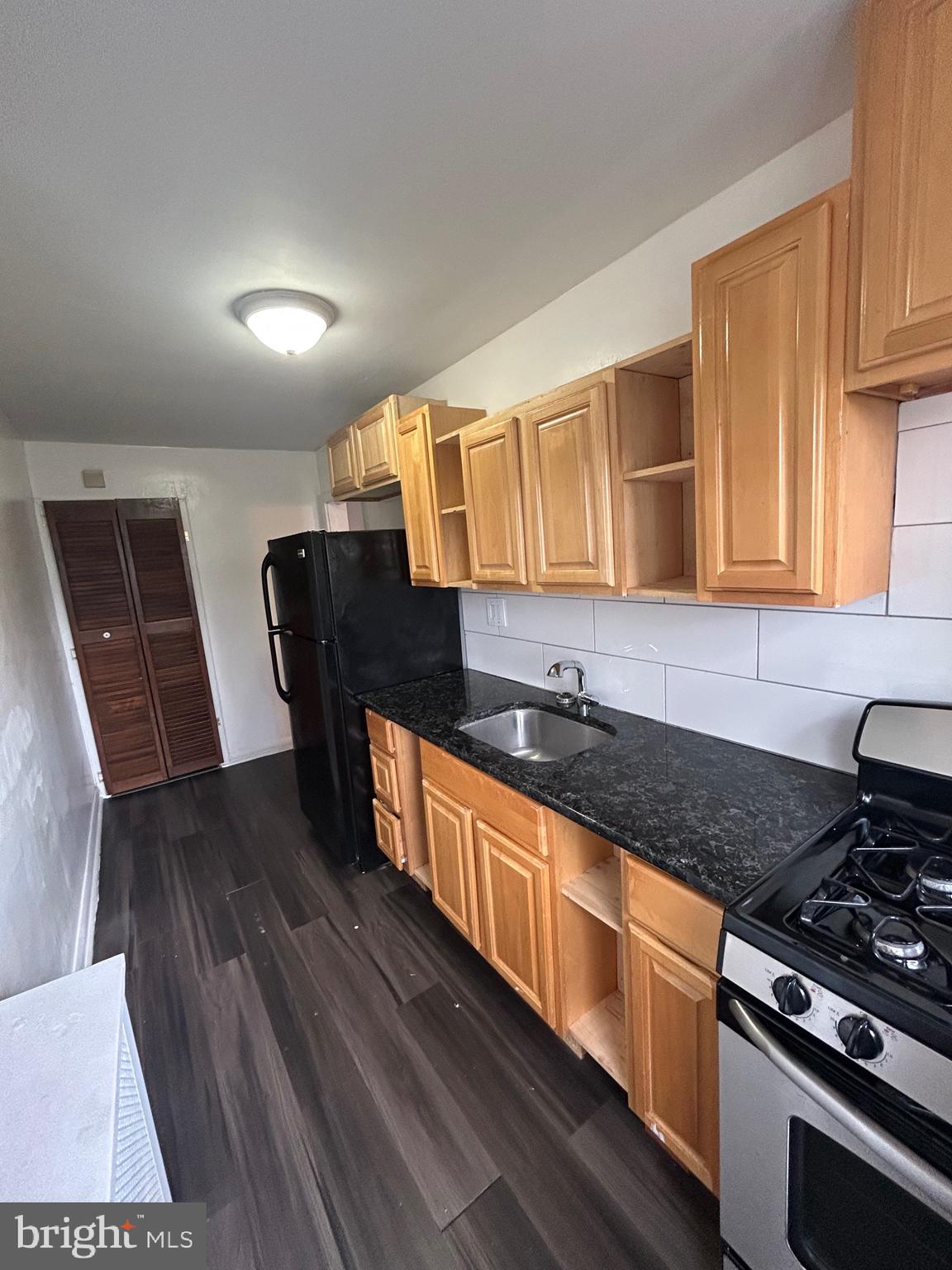 3902 8th Street Brooklyn, MD 21225 - Photo 5 of 11 a kitchen with granite countertop wooden cabinets a stove and a sink