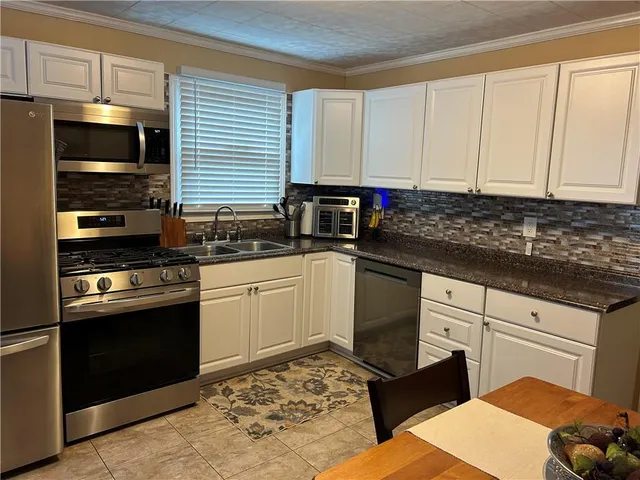 a kitchen with stainless steel appliances granite countertop a stove a sink and a microwave