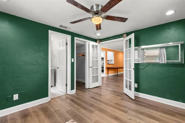 an empty room with wooden floor fan and windows