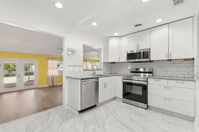 a kitchen with stainless steel appliances granite countertop a stove a sink and a microwave