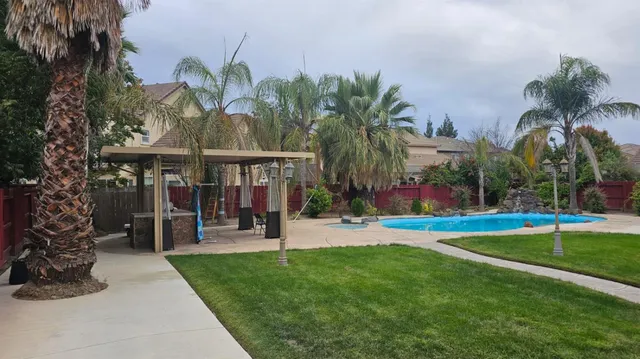 a view of a house with a yard and palm trees