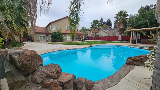 a view of swimming pool with lounge chair and dinning table under an umbrella