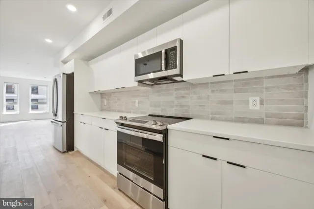a kitchen with stainless steel appliances white cabinets and a stove top oven