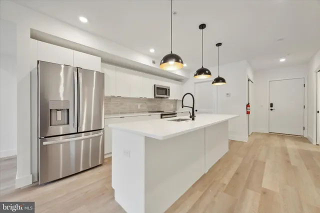 a kitchen with stainless steel appliances kitchen island a refrigerator sink and white cabinets