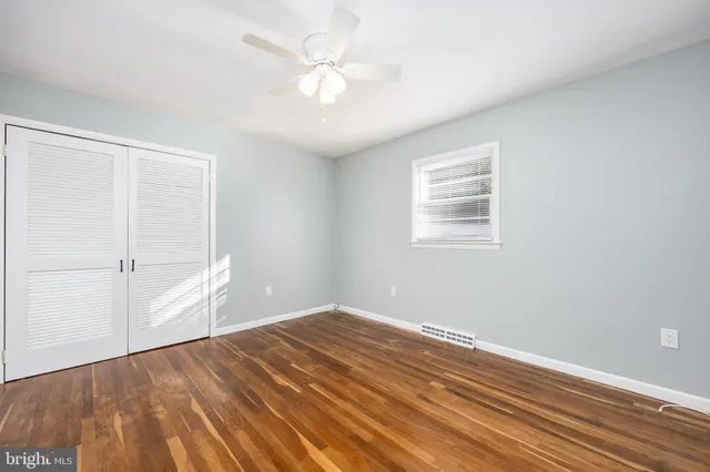 an empty room with wooden floor and fan