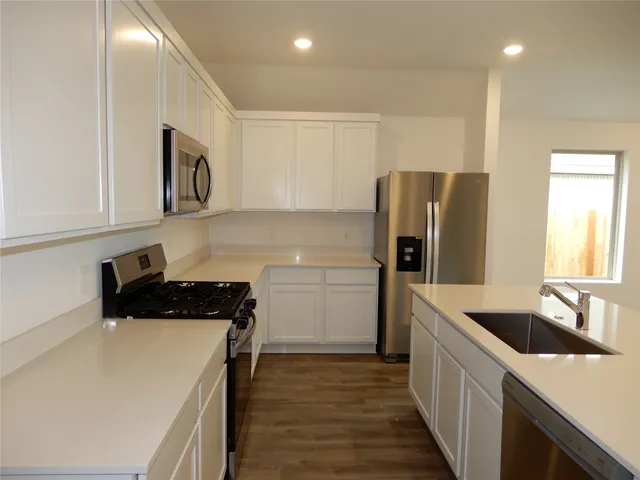 a kitchen that has a sink a refrigerator and cabinets