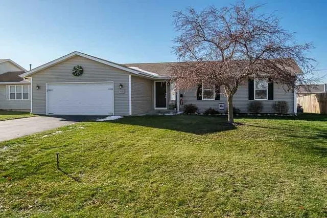 a front view of house with yard and trees in the background
