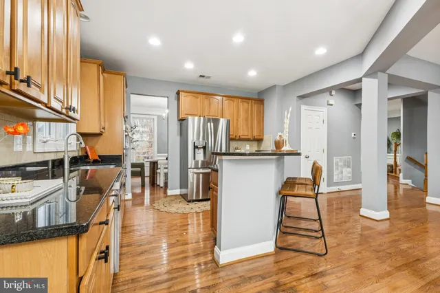 a kitchen with stainless steel appliances granite countertop a refrigerator a stove a oven and white cabinets with wooden floor