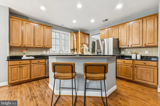 a kitchen with stainless steel appliances granite countertop a stove a sink dishwasher a dining table and chairs with wooden floor