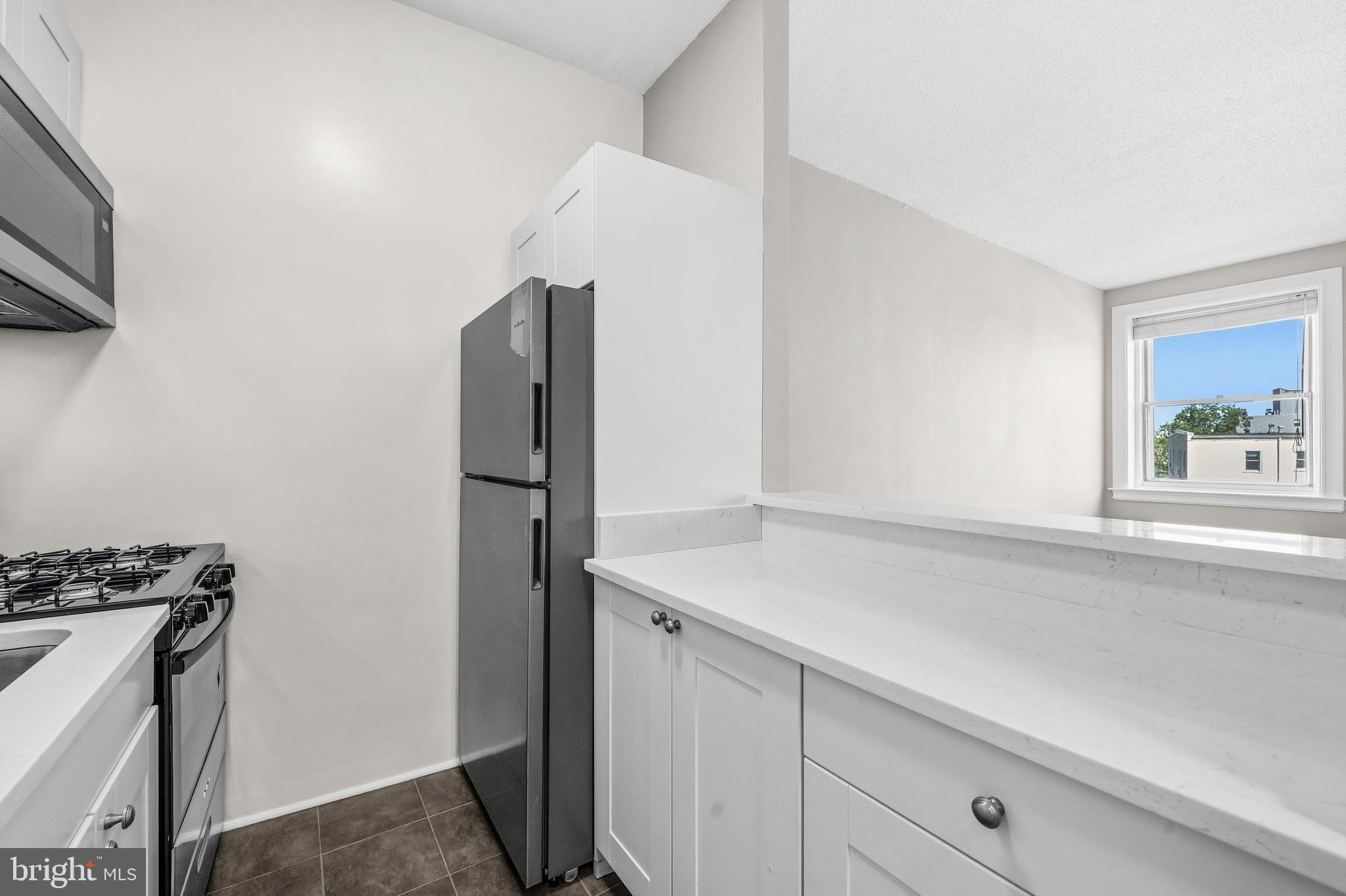 1851 Columbia Road Northwest, Unit 401 Washington, DC 20009 - Photo 10 of 27 a kitchen with stainless steel appliances a refrigerator and a stove