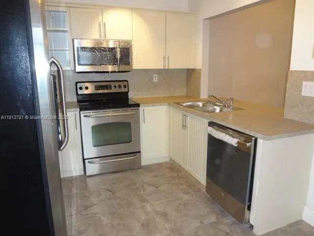 a kitchen with stainless steel appliances a stove microwave and sink