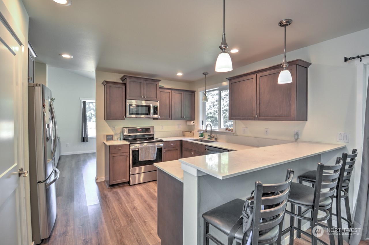 424 Brown Road East Chehalis, WA 98532 - Photo 11 of 25 a kitchen with stainless steel appliances granite countertop a refrigerator a sink dishwasher a stove and white countertops with wooden floor