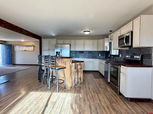 a kitchen with stainless steel appliances wooden floors a refrigerator and a stove top oven