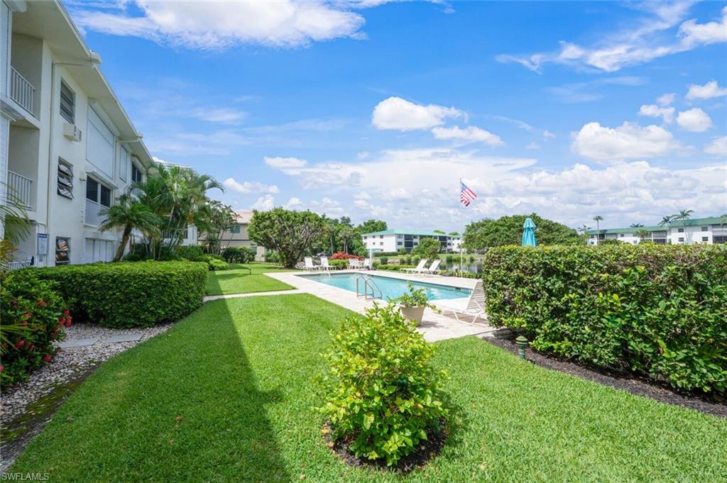 3055 Riviera Drive, Unit 306 Naples, FL 34103 - Photo 22 of 26 Community pool featuring a lawn and a patio