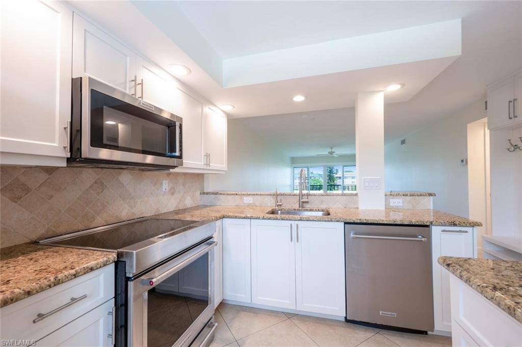 3055 Riviera Drive, Unit 306 Naples, FL 34103 - Photo 4 of 22 Kitchen featuring stainless steel appliances, white cabinetry, light stone countertops, light tile patterned floors, and recessed lighting