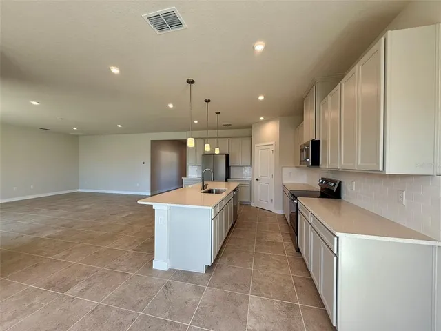 a large kitchen with a large counter top a sink a window and stainless steel appliances