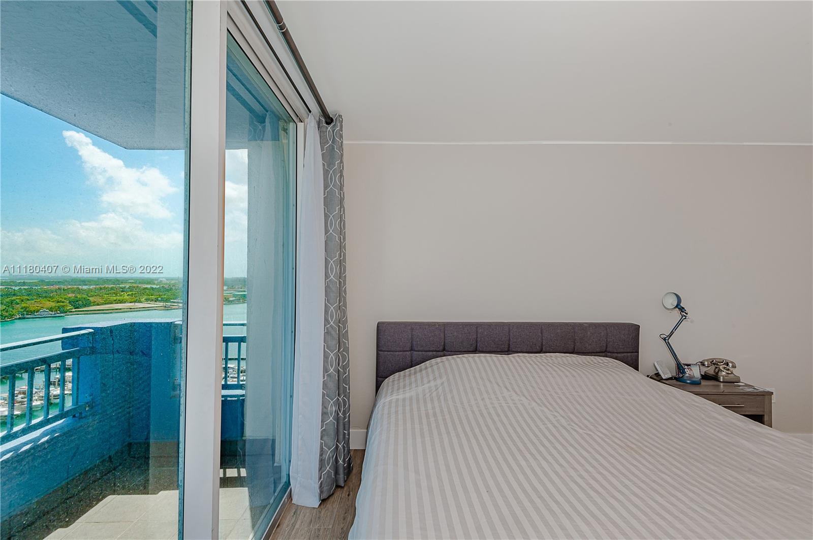 90 Alton Road, Unit 1901 Miami Beach, FL 33139 - Photo 14 of 21 a bedroom with a bed and glass door