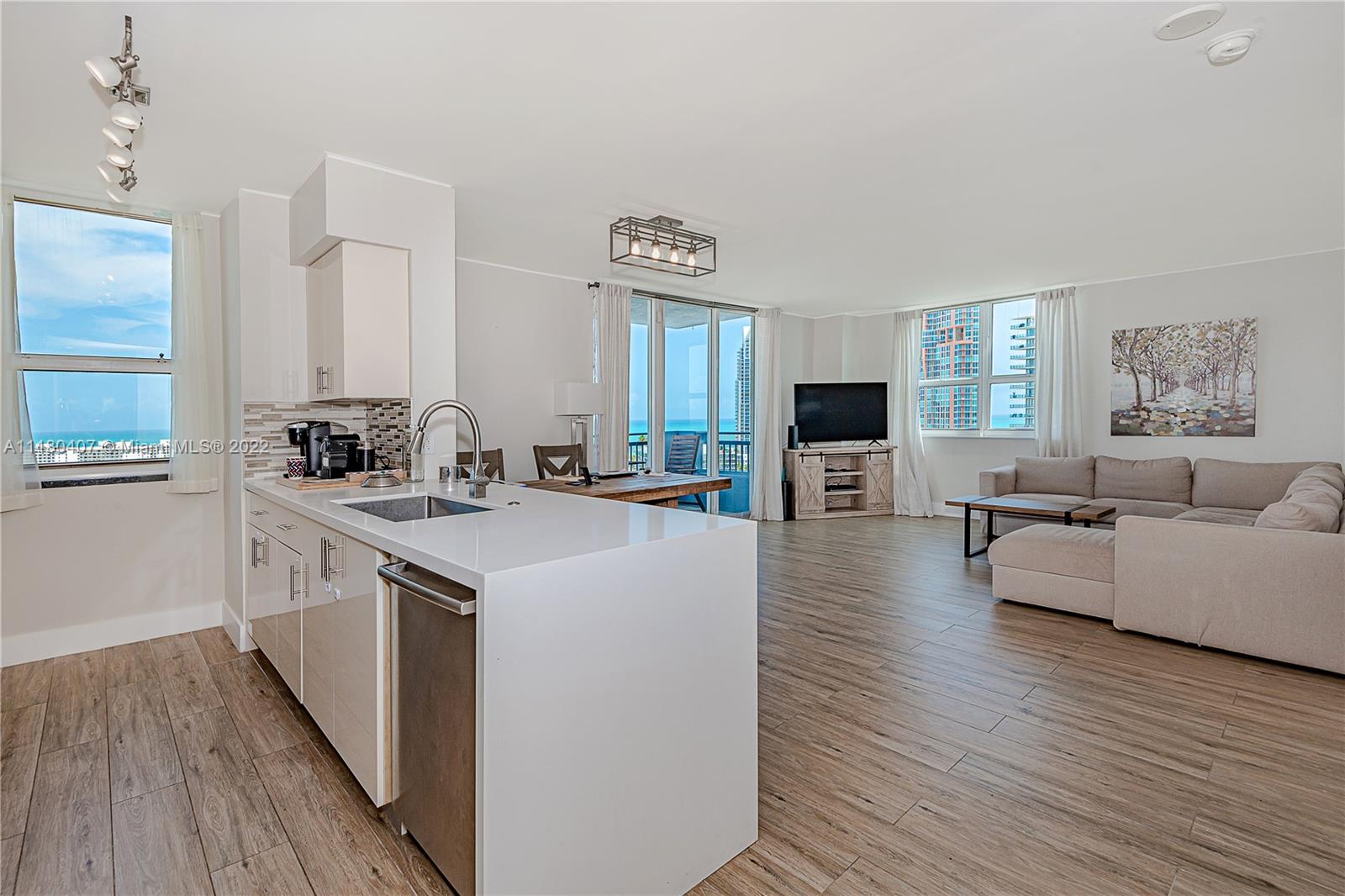 90 Alton Road, Unit 1901 Miami Beach, FL 33139 - Photo 6 of 21 a view of living room kitchen with stainless steel appliances furniture stove and wooden floor