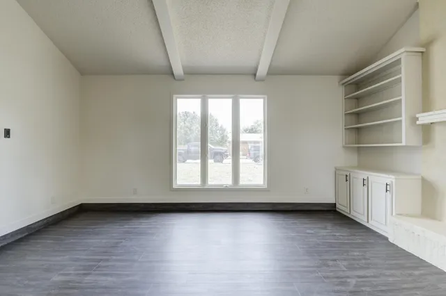 an empty room with wooden floor and window