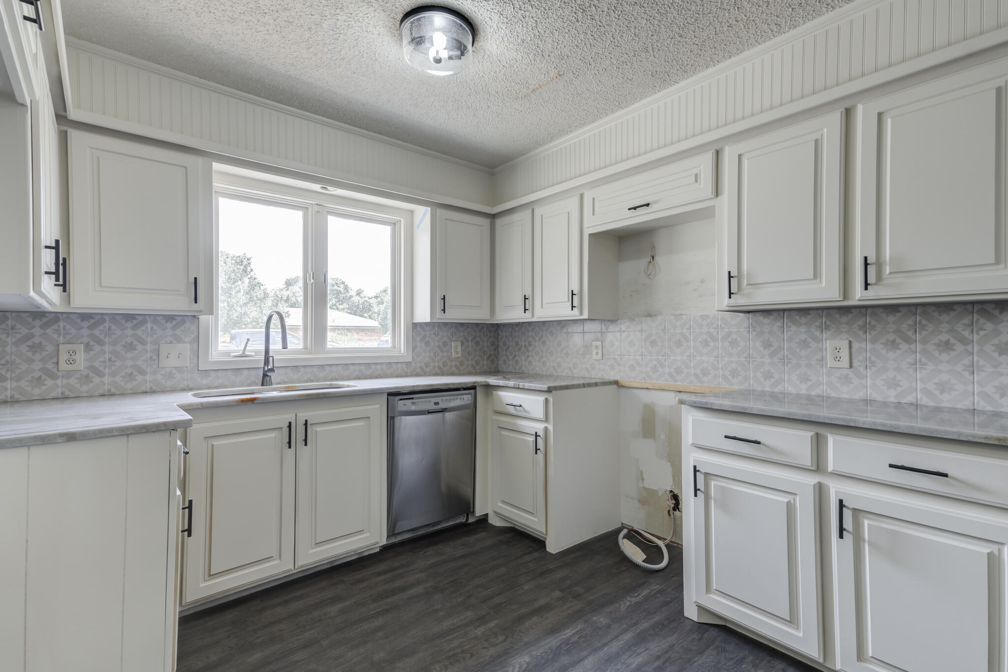 3006 93rd Street Lubbock, TX 79423 - Photo 18 of 35 a kitchen with white cabinets granite counter tops and a hard wood floors