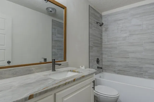 a bathroom with a granite countertop sink a toilet and shower