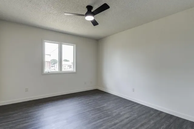 an empty room with a window and a ceiling fan