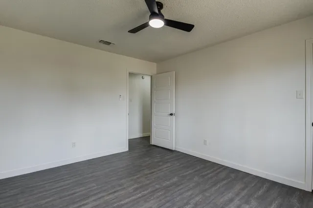 a view of an empty room and chandelier fan
