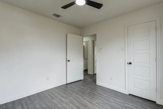 an empty room with wooden floor a ceiling fan and entryway