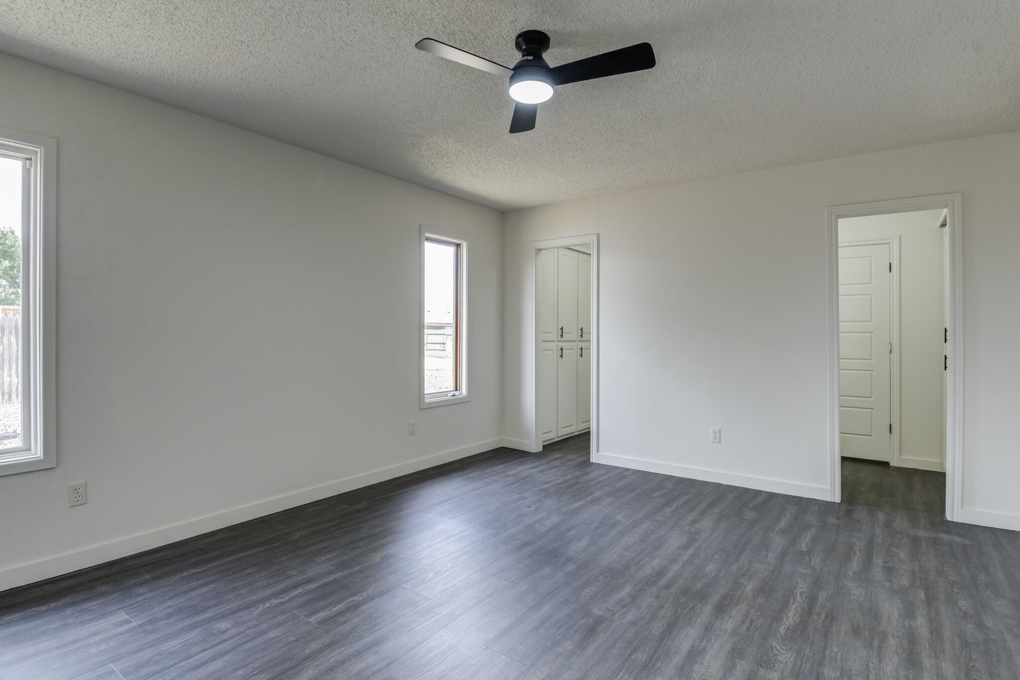 3006 93rd Street Lubbock, TX 79423 - Photo 30 of 35 an empty room with wooden floor ceiling fan and windows