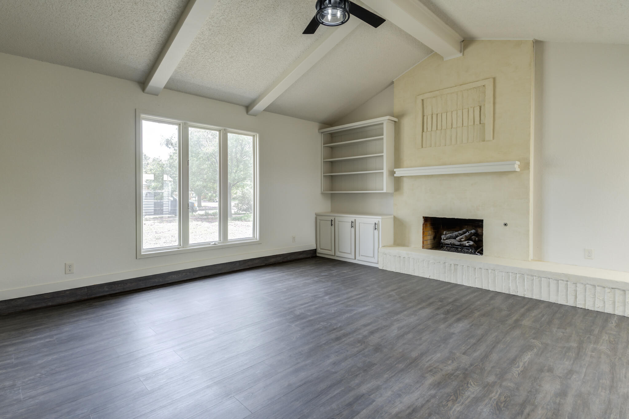 3006 93rd Street Lubbock, TX 79423 - Photo 4 of 35 an empty room with wooden floor fireplace and windows