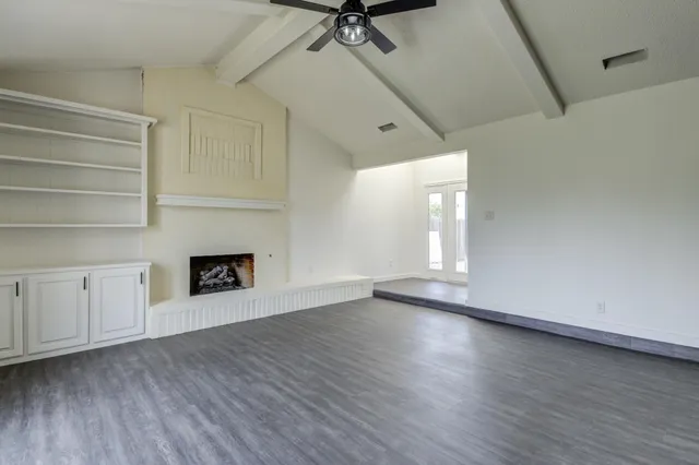 a view of an empty room with a window and fireplace