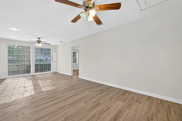 a view of empty room with wooden floor and fan