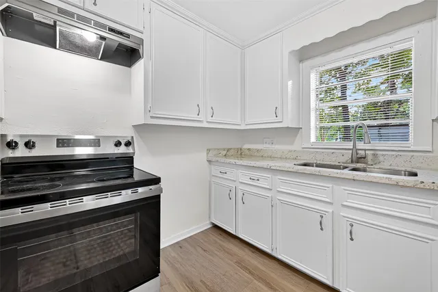 a kitchen with granite countertop a sink and white cabinets