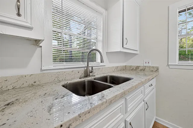 a kitchen with granite countertop white cabinets and sink