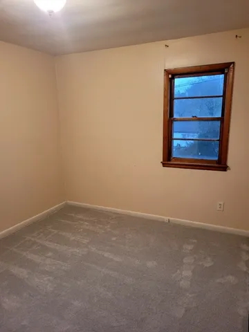 a view of an empty room with closet and a window
