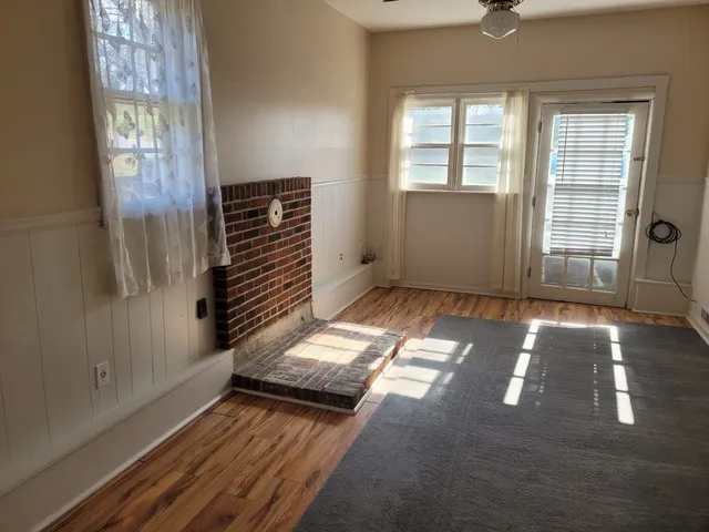 a view of an empty room with wooden floor and windows