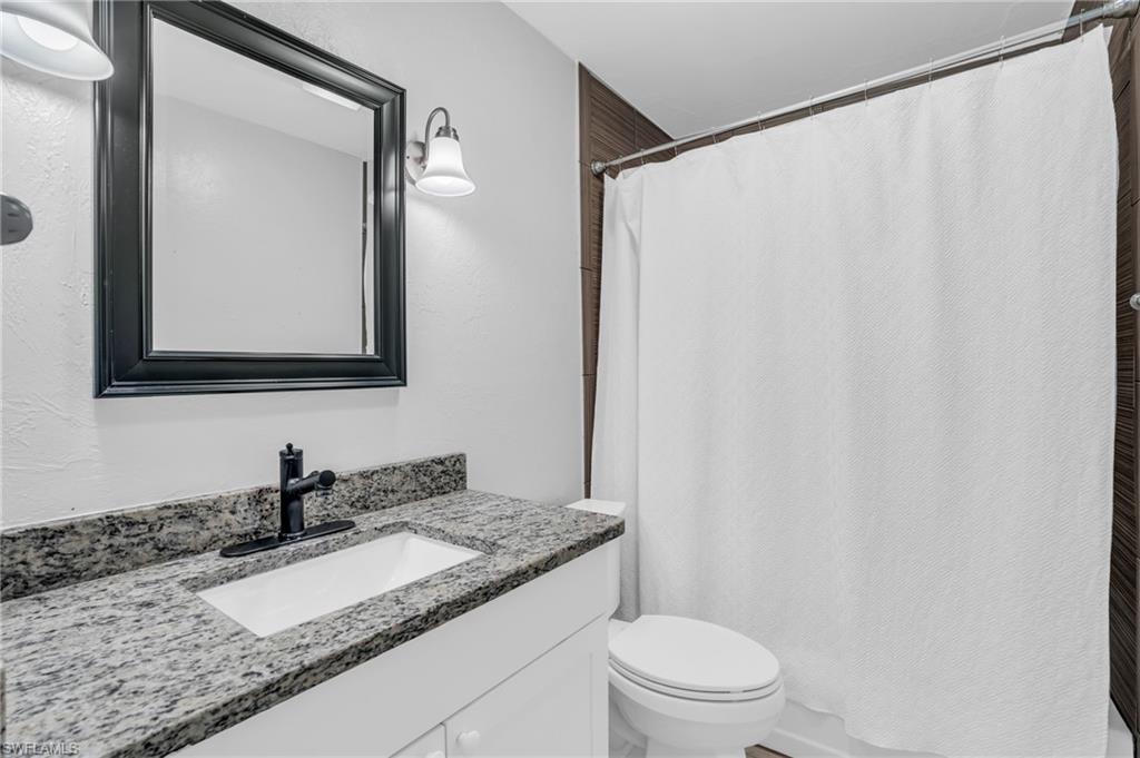 883 Coconut Circle East Naples, FL 34104 - Photo 26 of 32 a bathroom with a granite countertop sink and a mirror