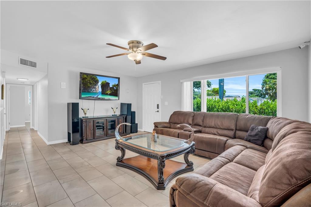 883 Coconut Circle East Naples, FL 34104 - Photo 3 of 32 a living room with furniture a fireplace and a flat screen tv