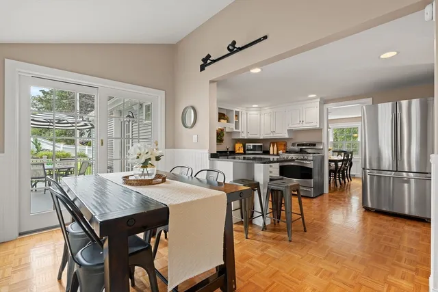 a kitchen with stainless steel appliances granite countertop a stove a refrigerator a kitchen island a table and chairs in it