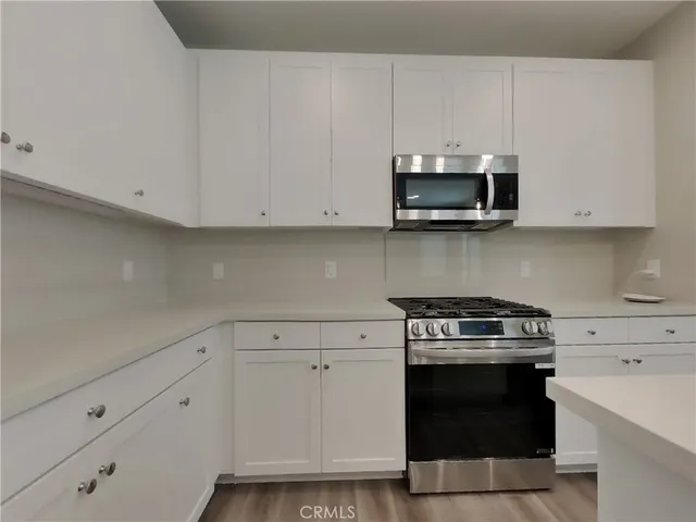 a kitchen with granite countertop white cabinets and stainless steel appliances