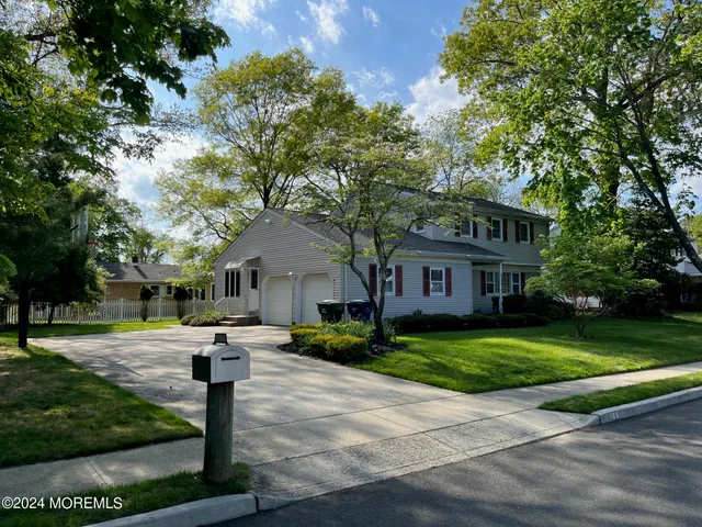 a front view of a house with a yard and trees