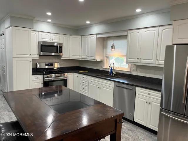 a kitchen with kitchen island granite countertop a sink a counter top space stainless steel appliances and cabinets