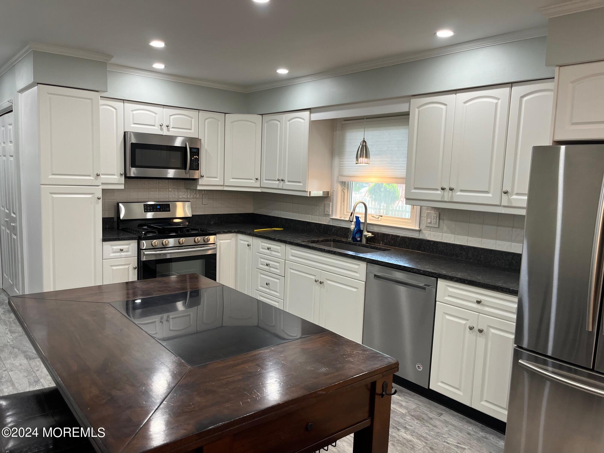 106 Pear Street Oakhurst, NJ 07755 - Photo 5 of 21 a kitchen with kitchen island granite countertop a sink a counter top space stainless steel appliances and cabinets
