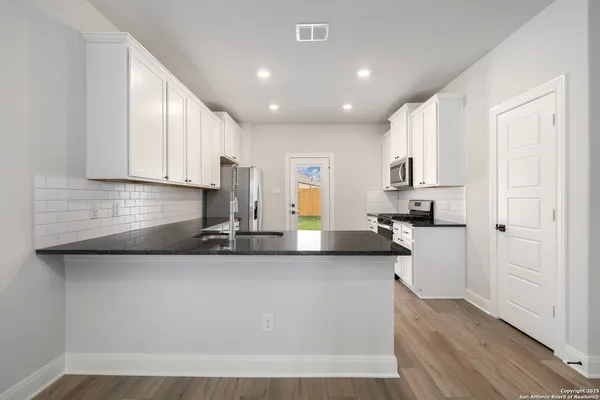 a kitchen with stainless steel appliances granite countertop a sink a stove and cabinets