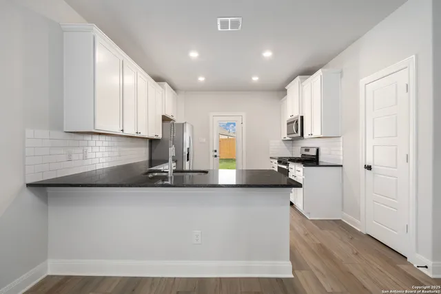 a kitchen with stainless steel appliances granite countertop a sink a stove and cabinets