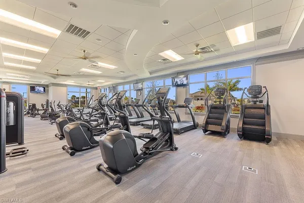 a dining hall with stainless steel appliances granite countertop a table chairs and a chandelier
